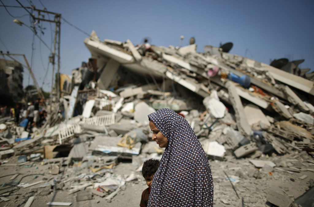 A Palestinian woman walks past the rubble of a residential building, which police said was destroyed in an Israeli air strike, in Gaza City