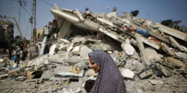 A Palestinian woman walks past the rubble of a residential building, which police said was destroyed in an Israeli air strike, in Gaza City